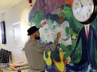 Hans Forsell jobbar med sin väggmålning i simhallens foajé.